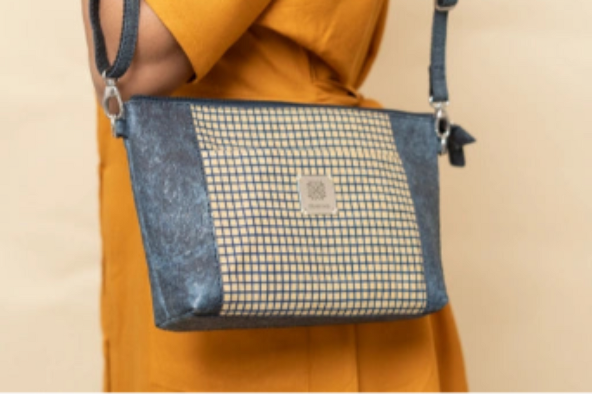 Person wearing a yellow garment with a blue and white checkered bag on a beige background